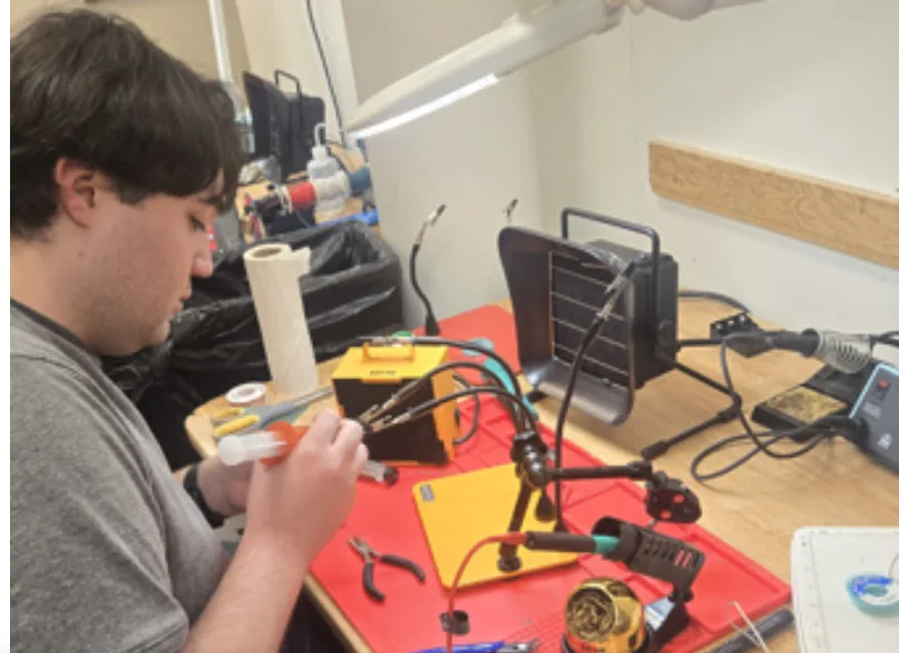 A member working at a fully set-up soldering station with fume extractor