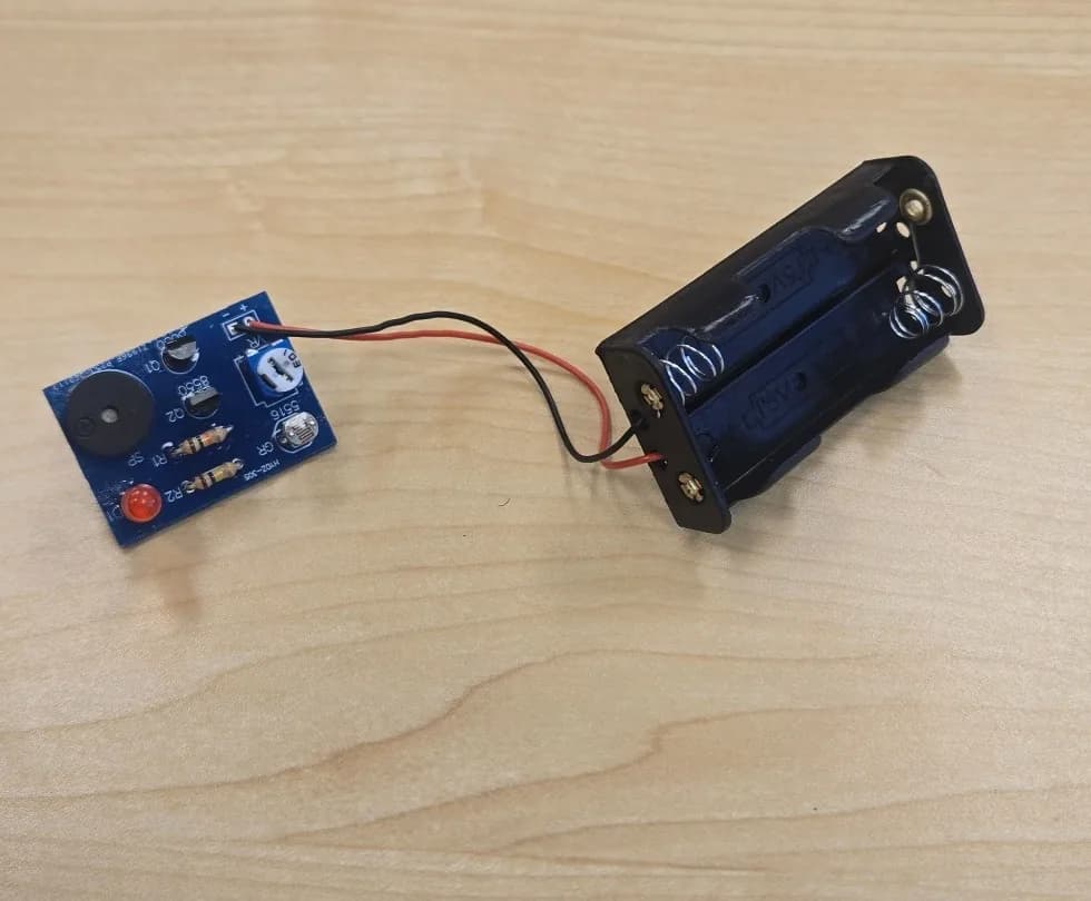 Completed light-activated alarm PCB connected to a two-cell battery holder